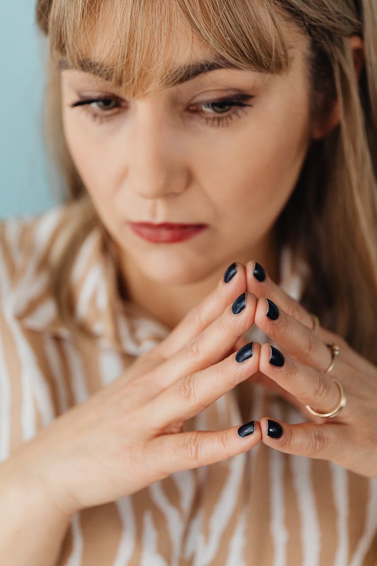 Thoughtful portrait of a woman with painted nails depicting contemplation.