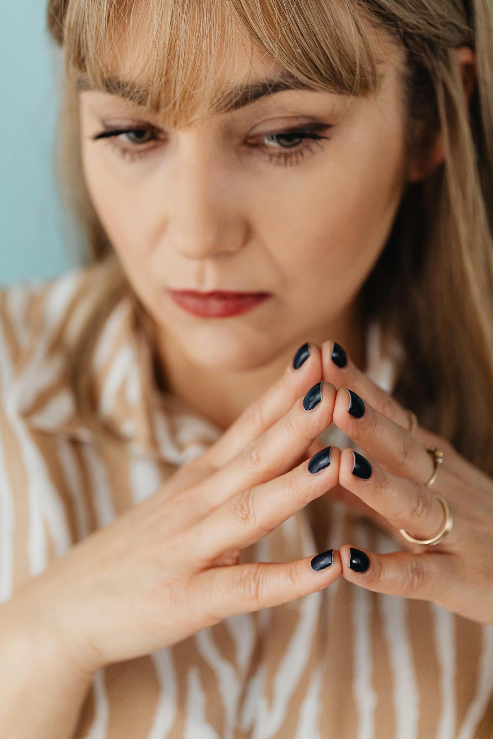 Thoughtful portrait of a woman with painted nails depicting contemplation.